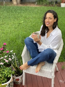 model wearing an elegant and chic  casual outfit of a white button down shirt and jeans. She's sitting down drinking a cup of tea.